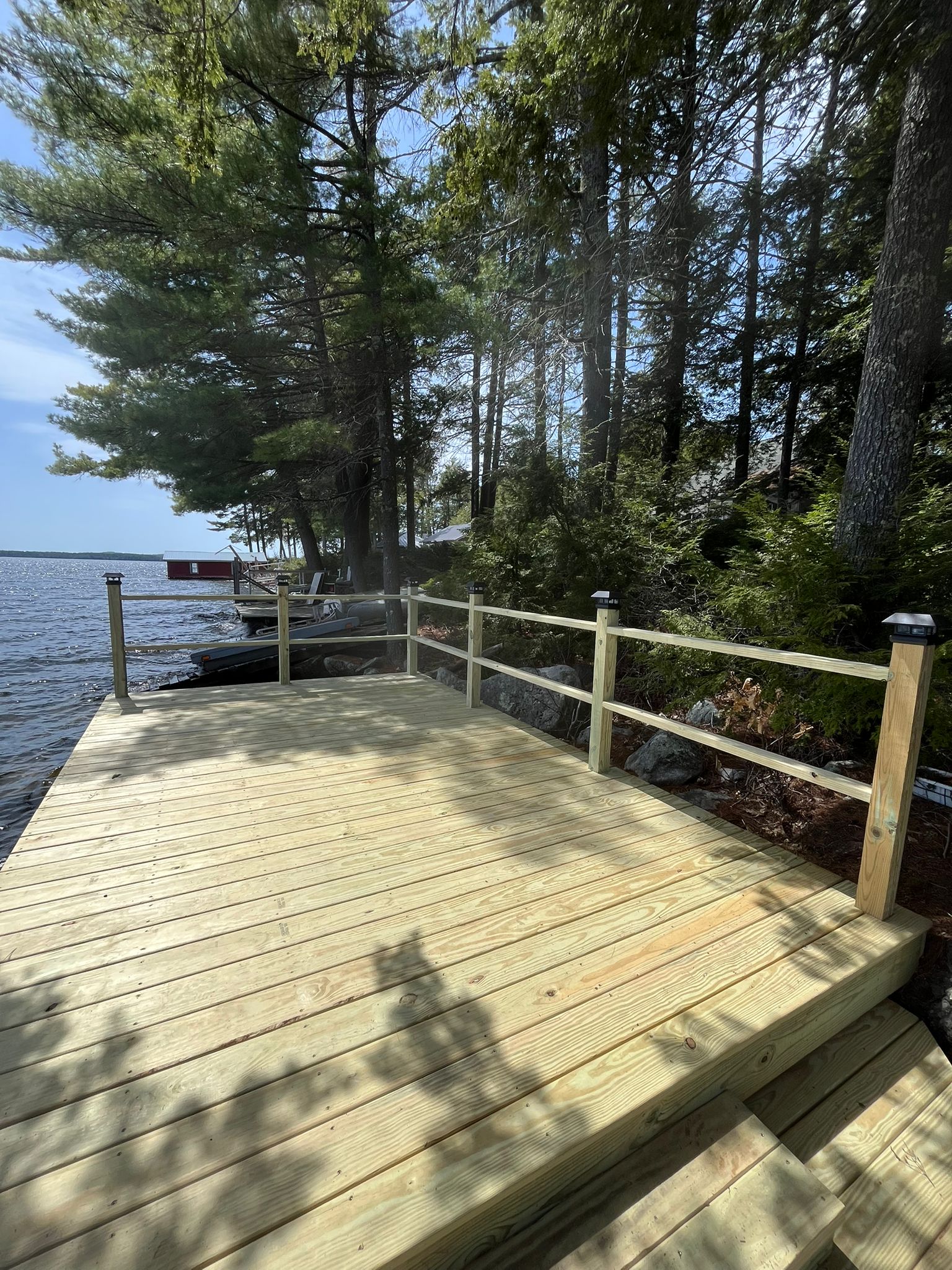 Lakefront dock with railings overlooking water and trees