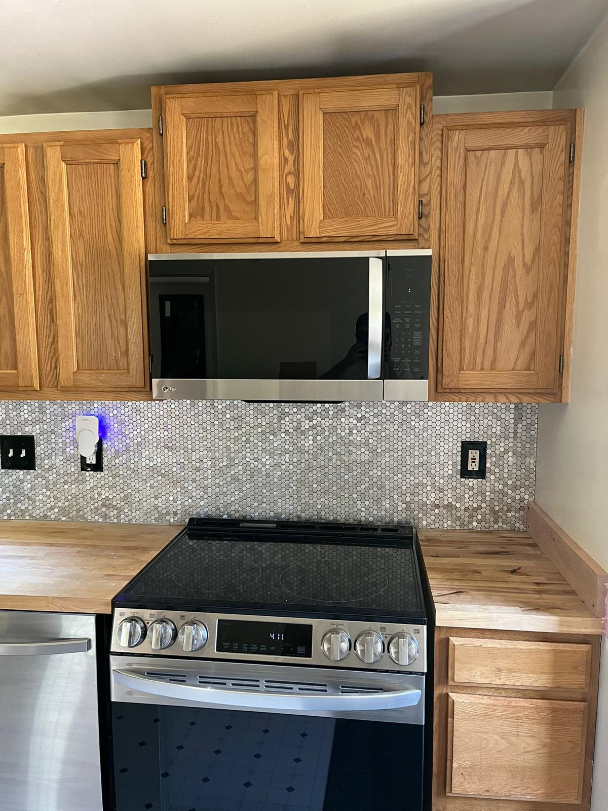 Kitchen with oak cabinets, stainless steel appliances, and mosaic tile backsplash