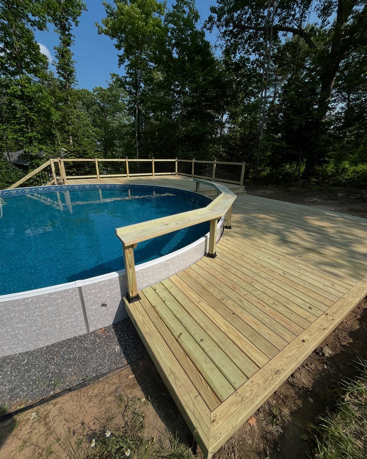 Custom wooden pool deck with curved design and safety railings