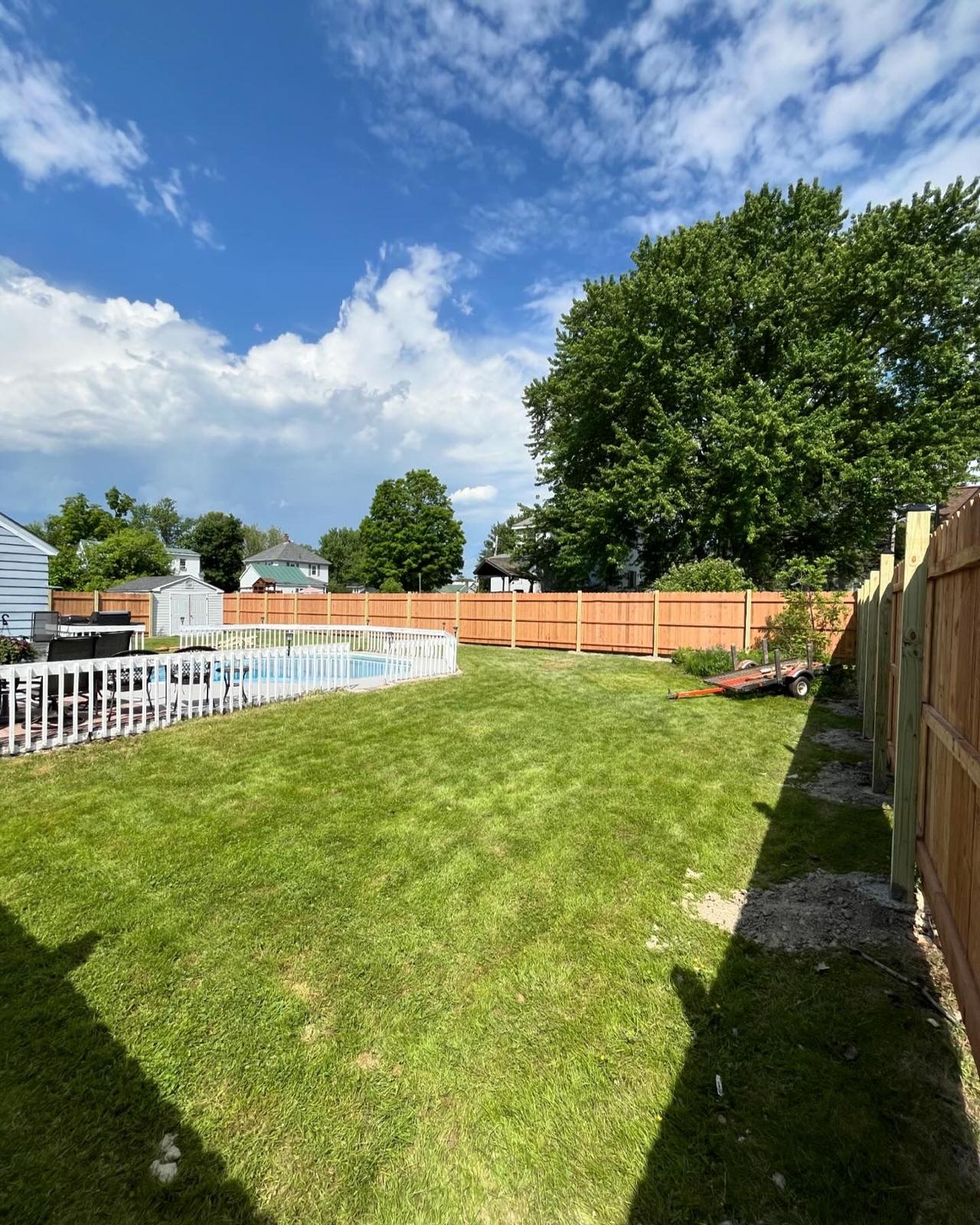 Custom wooden fence surrounding backyard pool area with landscaping