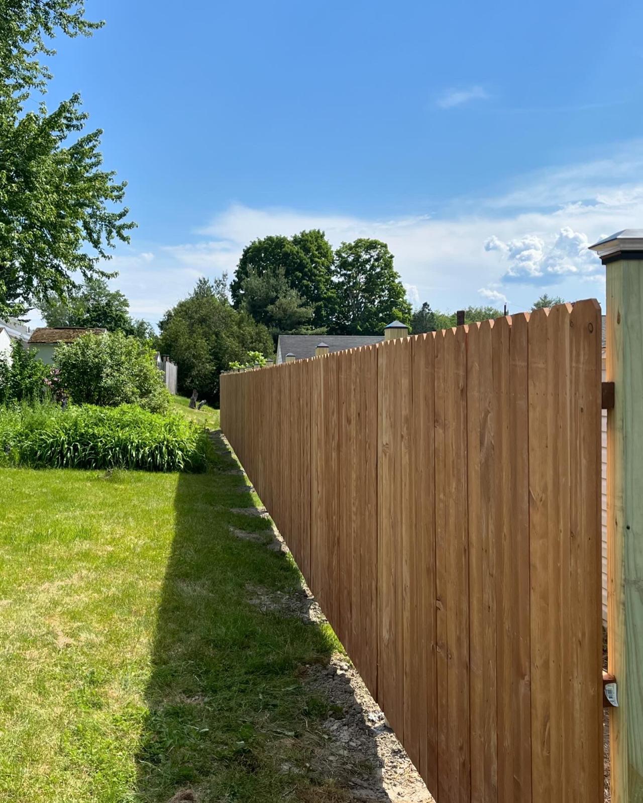 Tall wooden privacy fence with vertical boards and scalloped top