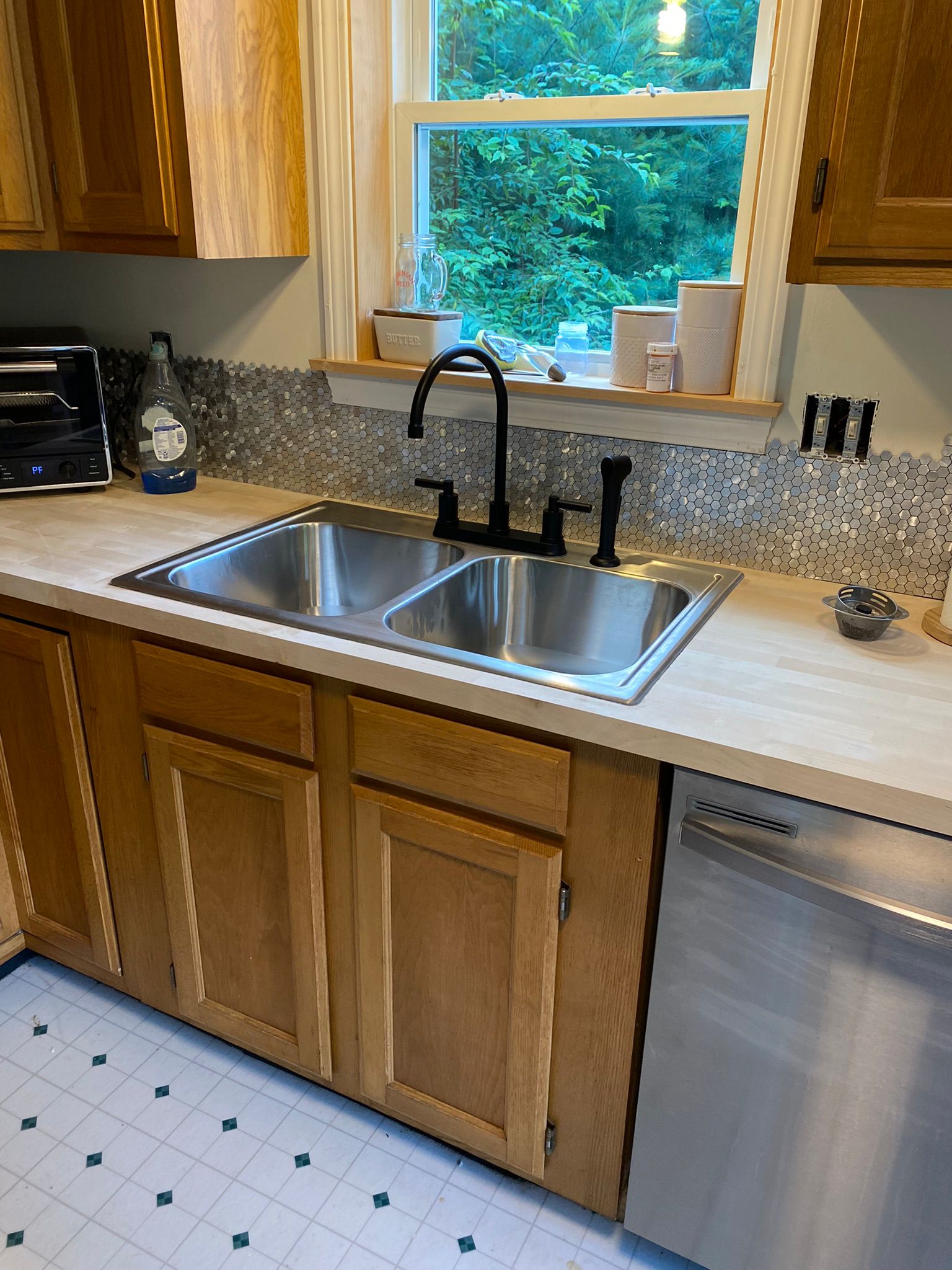 Kitchen sink area with decorative tile backsplash and oak cabinetry