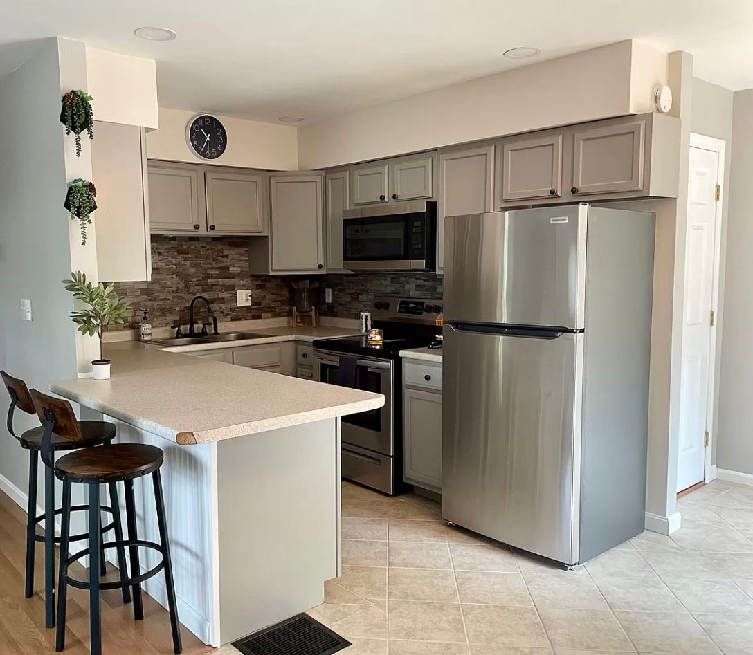 After - Modern kitchen with gray cabinets, stone backsplash and stainless appliances