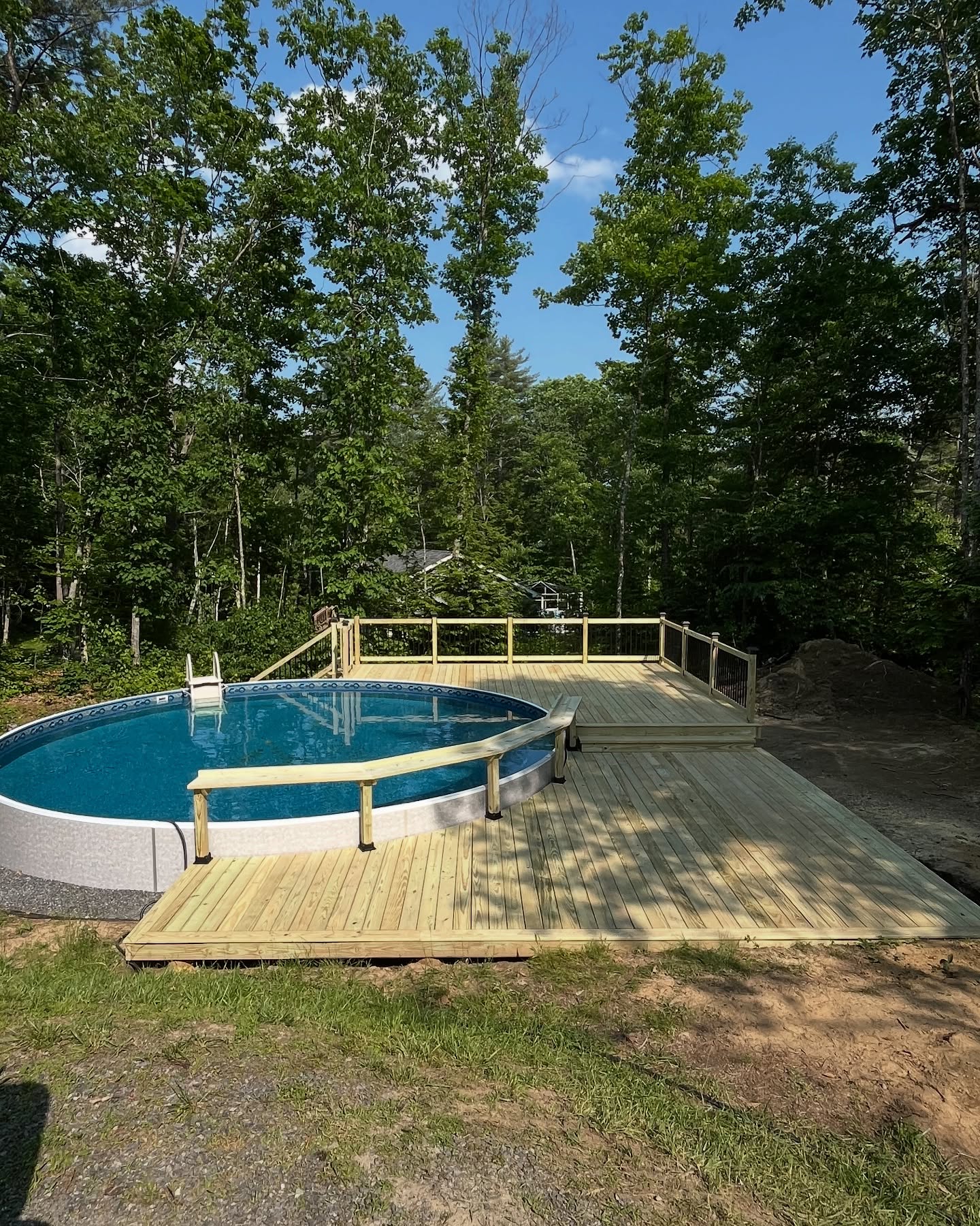 Elevated wooden pool deck with stairs and railings in wooded setting